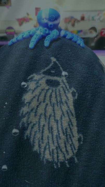 A small plushy squid on a water-themed blanket, underwater effect applied