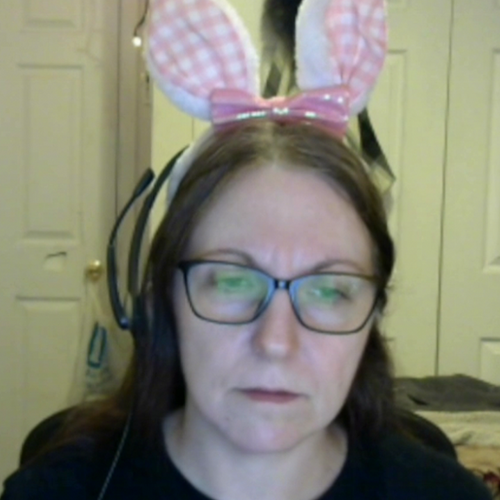 A woman with glasses and bunny ears, with a sad or focused expression