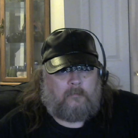 A bearded man in a ball cap staring into the camera