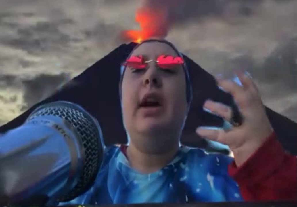 A person in flame sunglasses giving a press conference with a volcano in the background